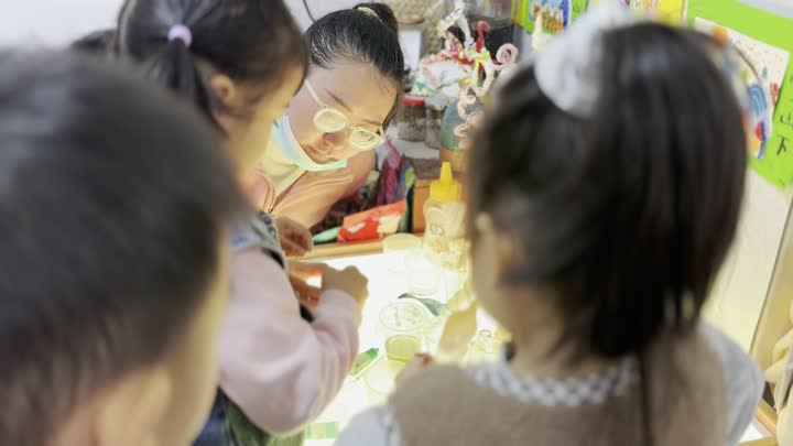 光台探究现场，教师俯身观察并支持儿童探索